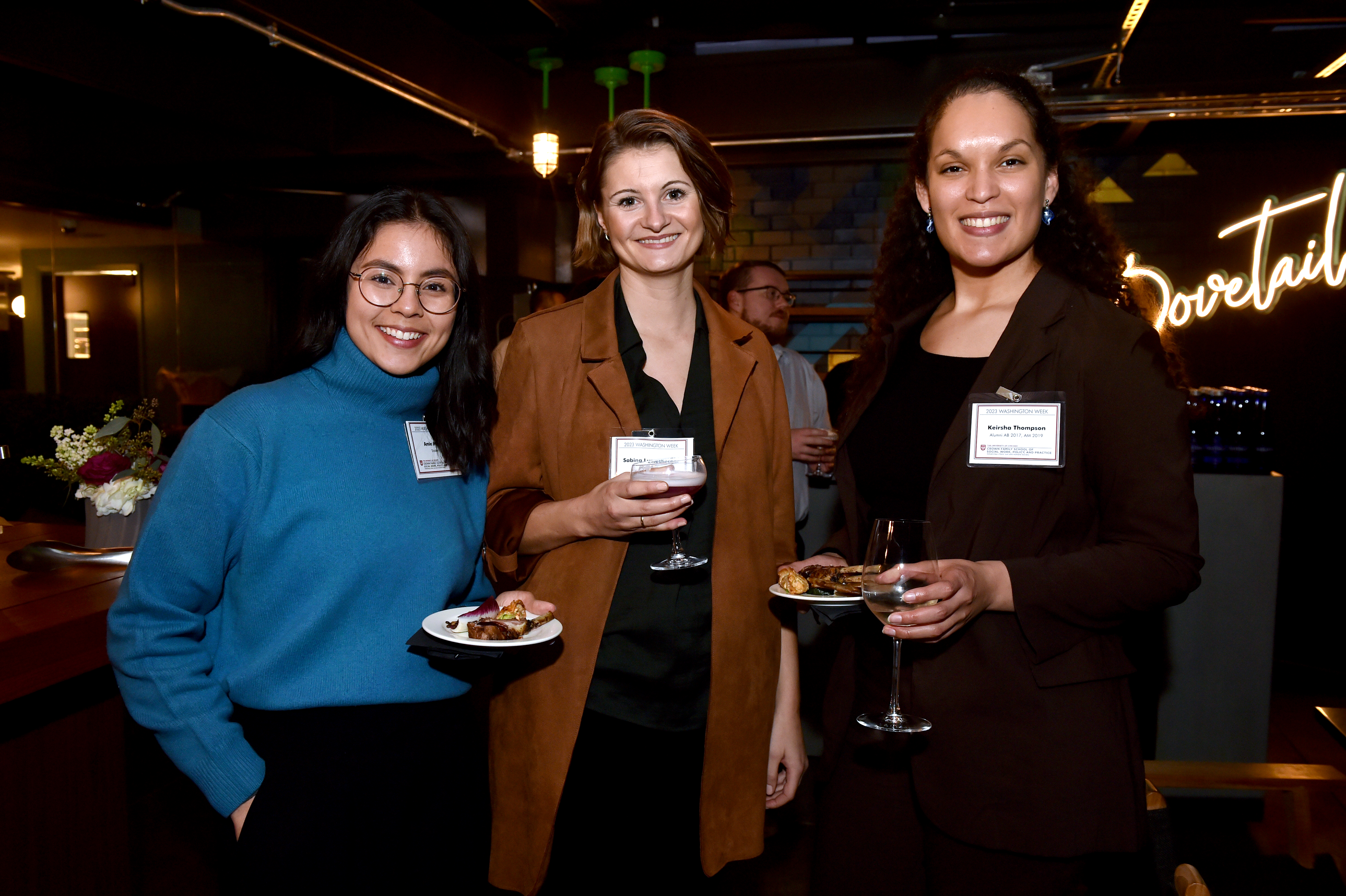 Image of three women, one in teal, one in brown and one in maroon eating appetizers