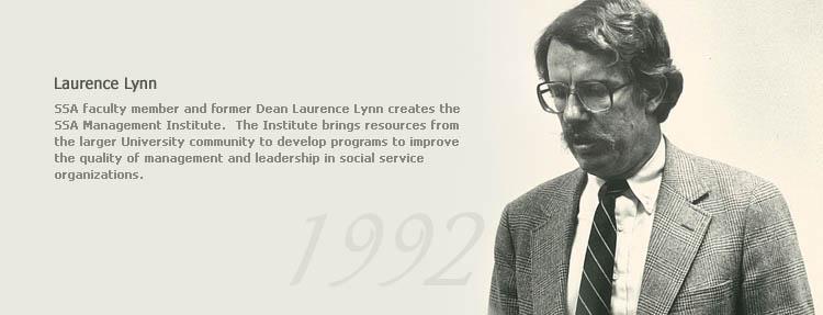 Image of Laurence Lynn dressed in a suit and tie glancing downward